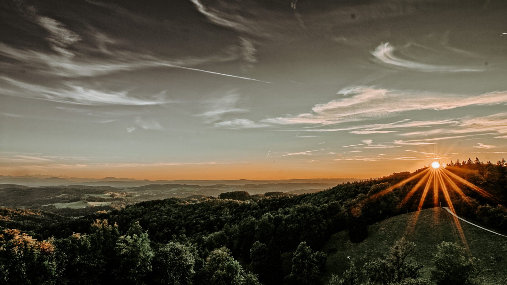 sunset over a rolling landscape with mountains